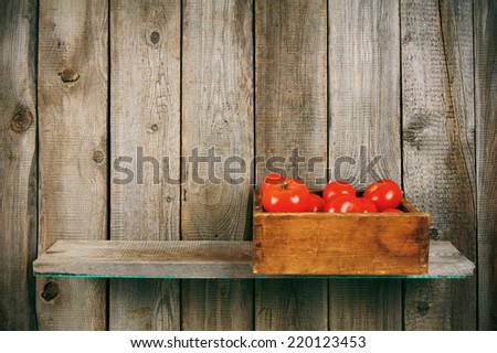 Tomatoes in an old box on a wooden shelf.