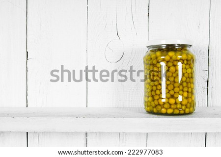 Preserved food in glass jar, on a wooden shelf. Marinaded peas