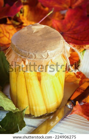 Autumn concept. Preserved food in glass jar on a wooden board. Marinated corn