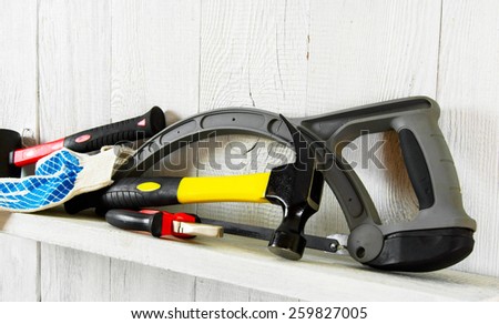 Working tools on a wooden shelf. On a white, wooden background.