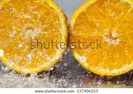 Fresh yellow orange splashing into water with water bubbles