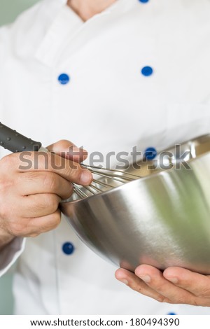 Cook whisking cream in the kitchen to make a cake