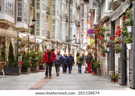 BURGOS, SPAIN - May 20of 2015: People walking on the street in the center of the city of Burgos decorated red flowers Spain. Burgos was the capital of the Castilla-Leon for 500 years.