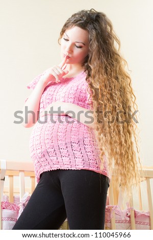 Pregnant woman with long hair near crib
