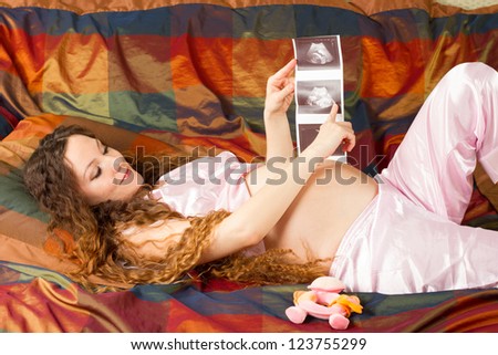 Pregnant woman and  belly with the ultrasound images in  hands at home. The concept of health and medicine