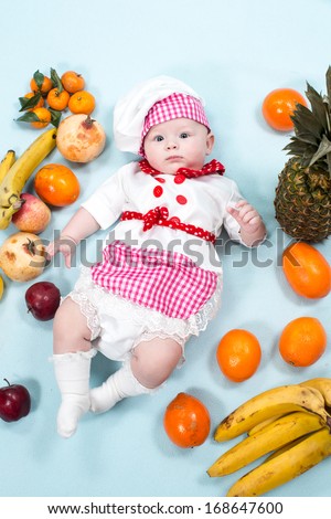 Baby cook girl wearing chef hat with fresh fruits. Use it for a child, healthy food concept .