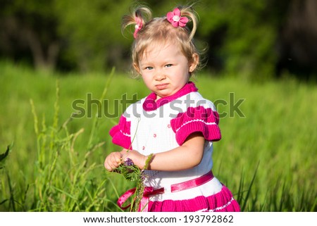 Portrait of little child girl on grass on meadow. Summer green nature background