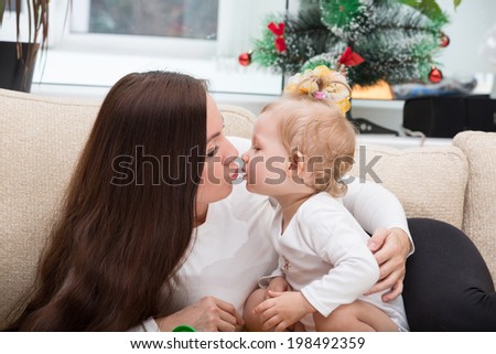 Happy mom and child girl hugging and kissing at home. The concept of cheerful childhood and family. Beautiful Mother and her baby