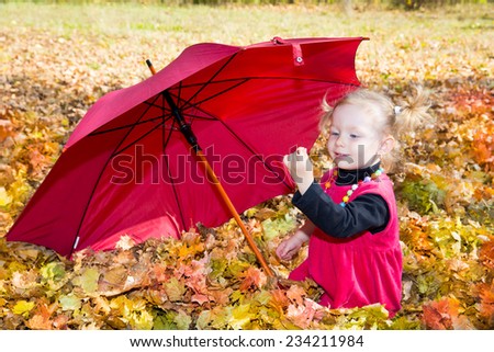 Fall. Cute child girl playing with fallen leaves in autumn park