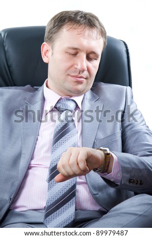 Close up portrait of a handsome young business man in a stylish suit  look on watch on his hand , isolated on white.
