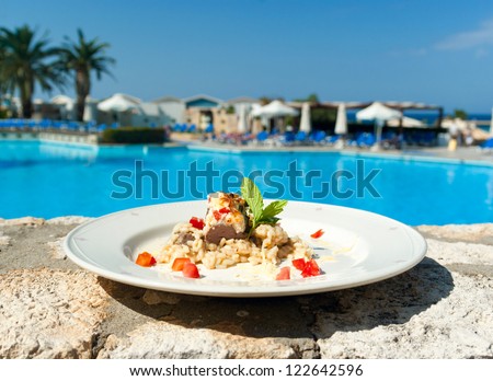 The dish with rice and meat near swimming pool in five stars hotel. Greece