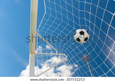 Football ball hit the goal net. Against blue sky