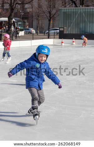 HELSINKI ,FINLAND-MARCH 29 2014:Children skate on an outdoor ice rink,HELSINKI ,FINLAND-MARCH 29 2014. In the cities of Finland it is opened in the winter works hard outdoor ice rinks.