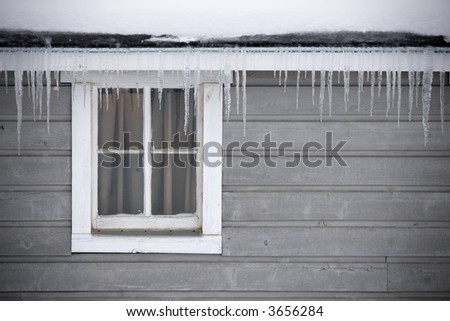 The roof of an old shed drips with icicles on a very cold day.