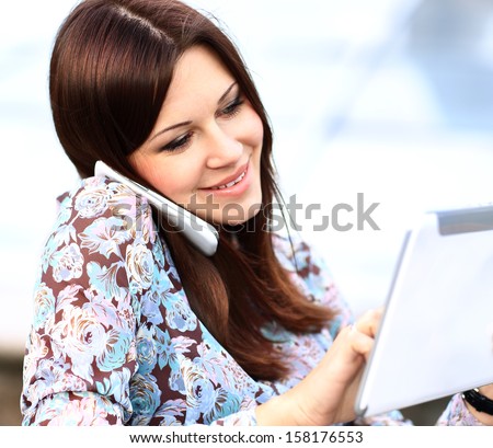 young businesswoman using digital tablet and mobile phone over building background