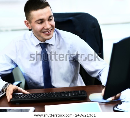 Casual businessman working in office, sitting at desk, typing on keyboard, looking at computer screen