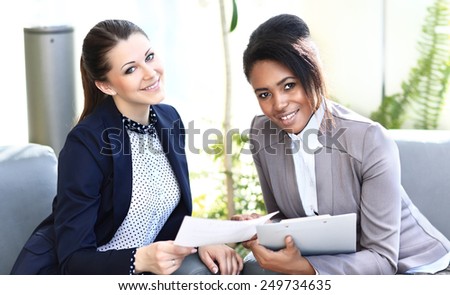 Image of two friendly businesswomen sitting and discussing new ideas