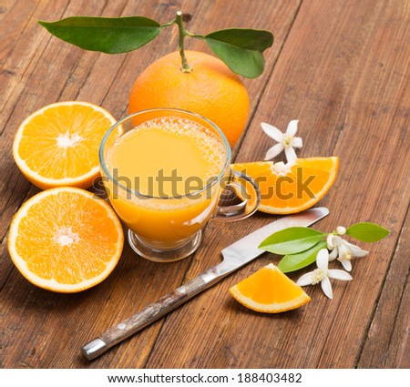 Fresh orange juice, orange with leaves and blossom on the wooden table