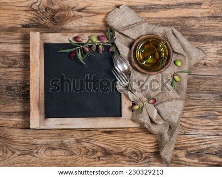 blackboard for menu on wooden table with olives, olive oil , knife and fork  over wooden table