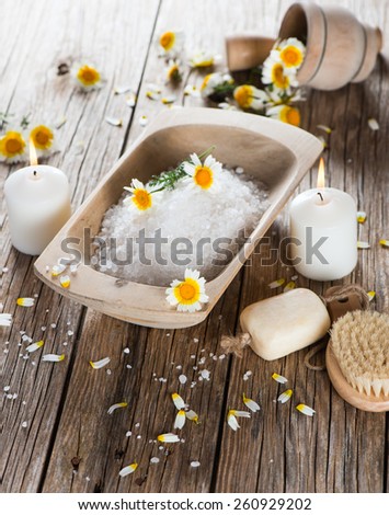 Spa relaxation theme with flowers, bath salt, soap and candles on wooden background