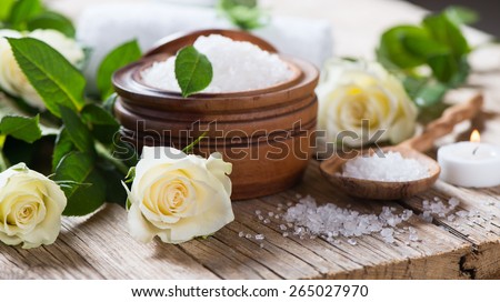 Spa relaxation theme with roses, bath salt and candle on a wooden background