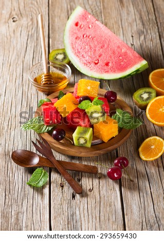 Various fresh multicolored fruits and mint on a wooden  platter on a old table