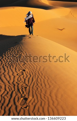 Arabian woman walking on the dunes of Sahara desert in Morocco