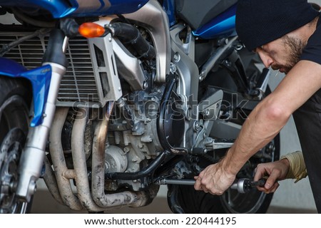 Serious young man repairing his motorcycle
