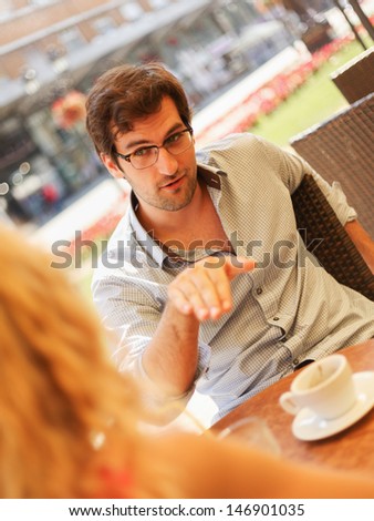 Portrait of a handsome young man sitting with his girlfriend in cafe