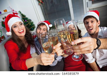 Young people wearing Santa\'s hats having a toast with champagne on new year\'s eve.
