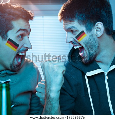 Two young men watching sports competition and drinking beer.