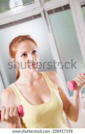 Beautiful Young Woman Exercising At Home With Dumbbells