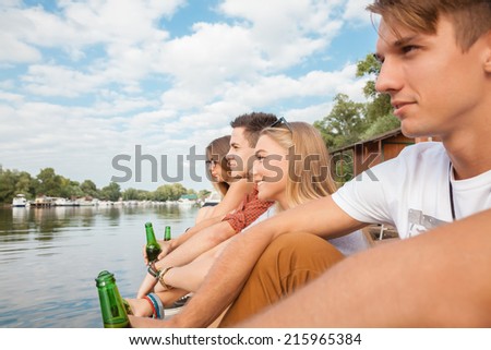 Group Of Cheerful Friends Chilling Near Lake