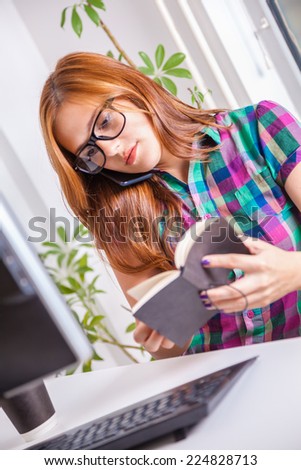 Young Female Graphic Designer Working In Office And Having Phone Conversation