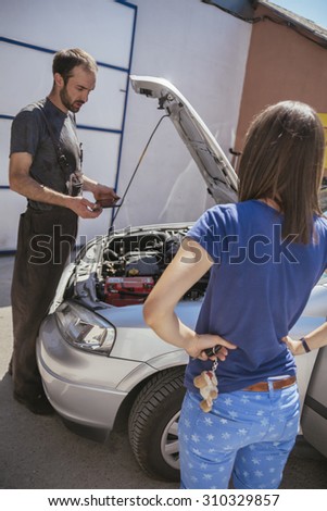 Auto Mechanic With Female Customer Checking Out Engine Problems Using Digital Tablet
