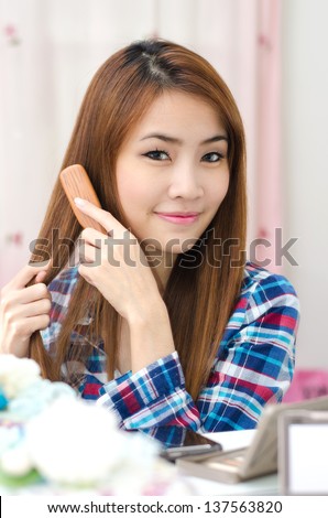 Young Asian girl combing hair in the dressing room