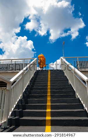 Monks is steps up the stairs of the pedestrian overpass in the city.