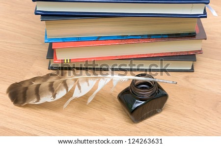 pen, ink and a stack of books on the background of wooden boards