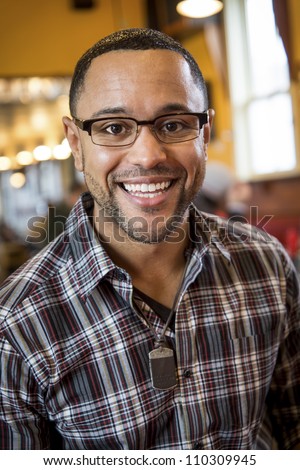 Portrait of smiling young black man in the interior of coffee shop.