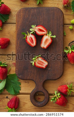 Culinary background with fruit. Ripe strawberries on cutting board. Top view. Old wooden table.