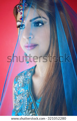 Portrait of a beautiful young woman of Asian origin wearing traditional clothing and jewelry in blue colors.