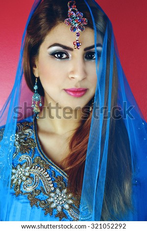 Portrait of a beautiful young woman of Asian origin wearing traditional clothing and jewelry in blue colors.