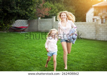 Mom and daughter running in the garden.