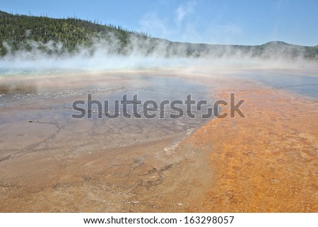 The rust colored minerals, blue water and steam of the Grand Prismatic Geyser at Midway Geyser Basin in Yellowstone National Park.