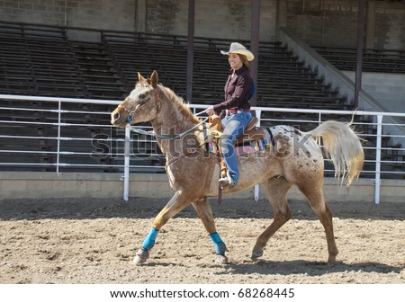 A cowgirl riding a horse in an arena.