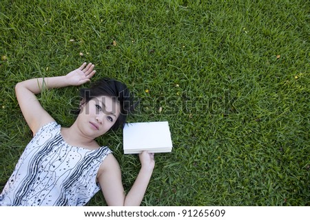Young woman reading a book in the field