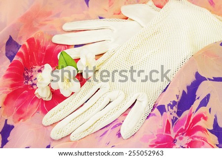Vintage lace gloves and artificial flowers of jasmine on vintage textile