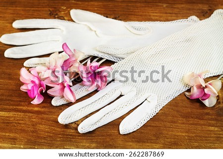 Old white gloves and artificial flowers on wooden background