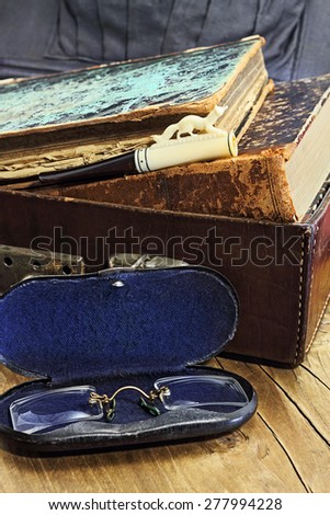 Leather suitcase with old books, a cigarette holder and pince-nez in a metallic case