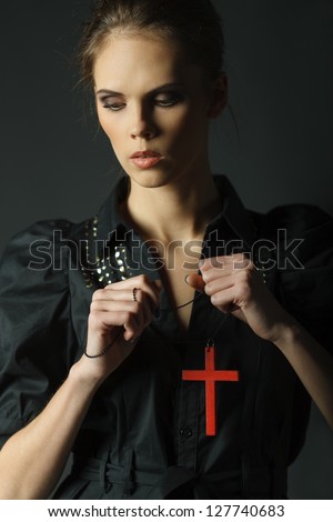 Closeup of fashion model posing over dark background with cross pendant